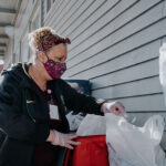 Gina, an employee of Woodburn School District's Nutrition Services department, helps distribute meals at AWARE Food Bank.