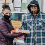 Staff member Mary Ann, left, and client Leonardo stand outside the AWARE Food Bank, Jan. 26, 2021. Verbal only release.