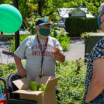 Pedro, left, speaks with Diabetes Support Services volunteer driver Jan while receiving a food box delivery.