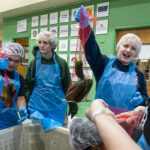 South Salem High School Developmental Learning Center students Abe, left, and Kellyn, right, bag cucumbers with help from student intern Kate, center.