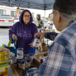 Kathey, left, fills her bag with assistance from volunteer Merri, right, during a pop-up distribution in west Salem.