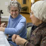 Capitol Manor residents Jeannie, left, and Bobbie share a laugh during a volunteer shift labeling bulk food bags.