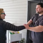 John, right, thanks volunteer driver Claire while receiving a delivery of groceries at his apartment in Salem. 